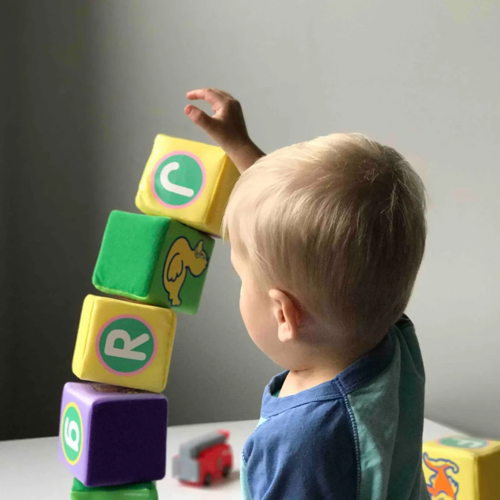 Un jeune enfant qui empile des cubes colorés sur une table.